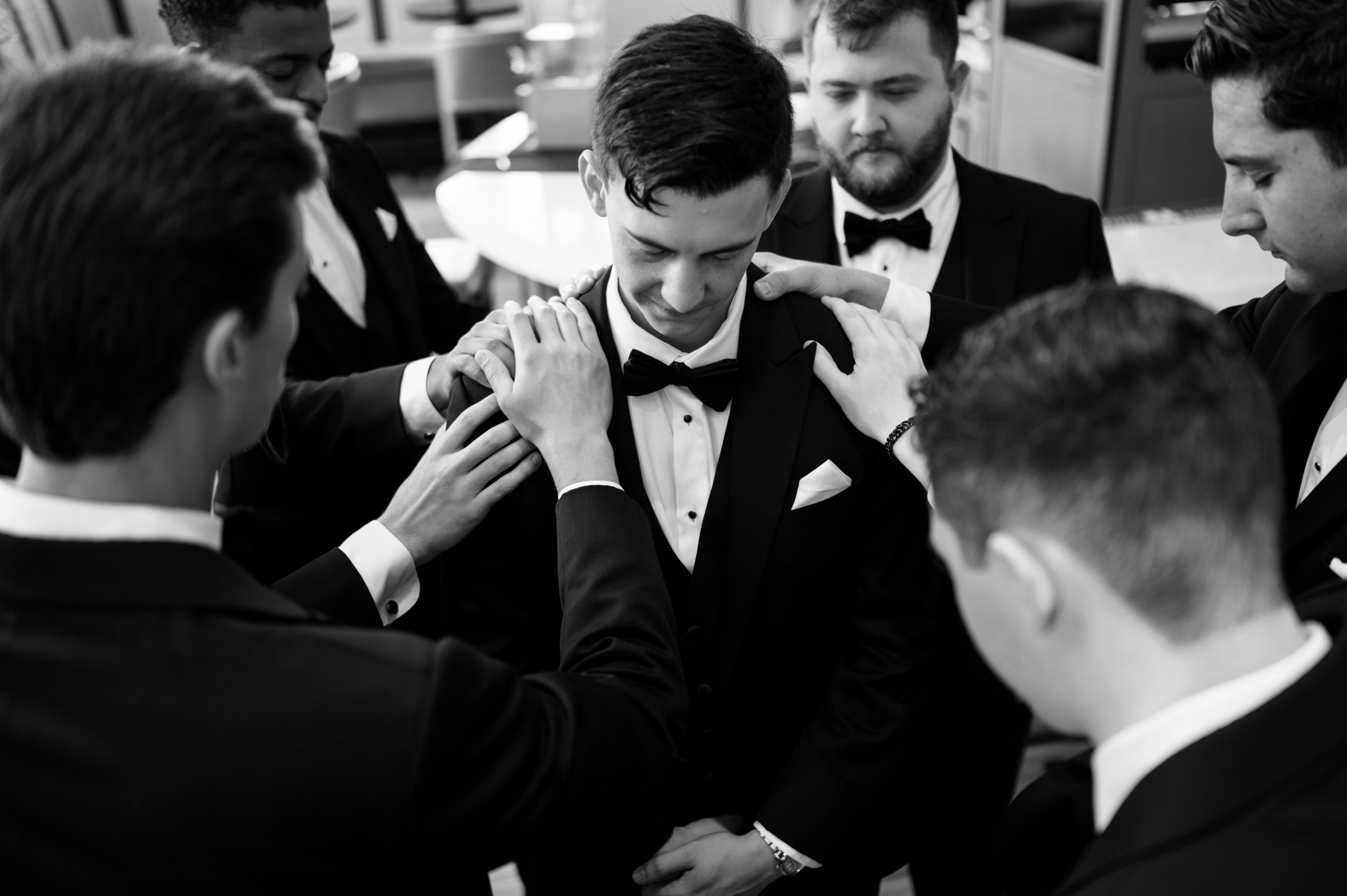 groomsmen praying over groom