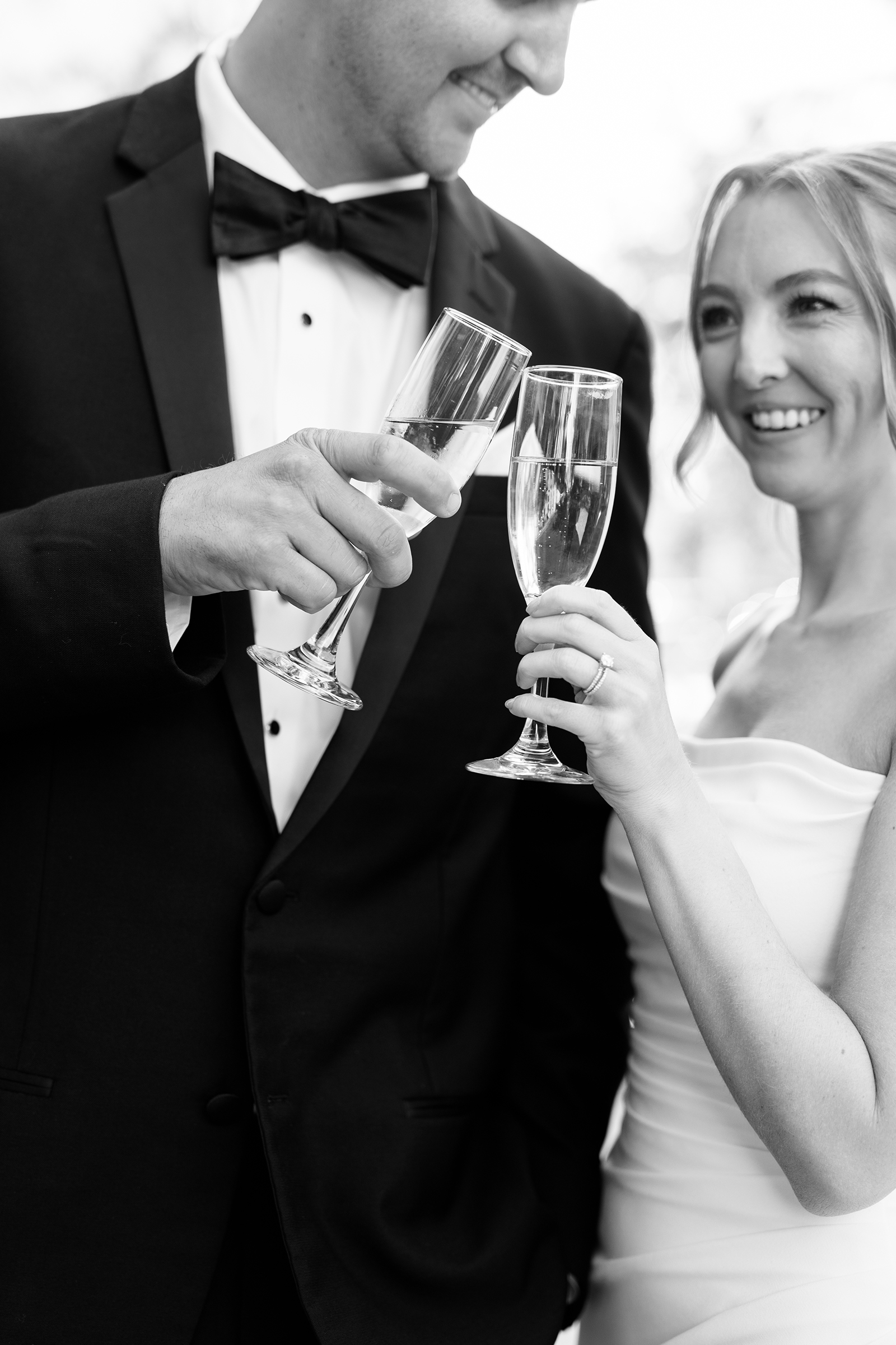 black and white portrait of bride and groom with glass of champagne