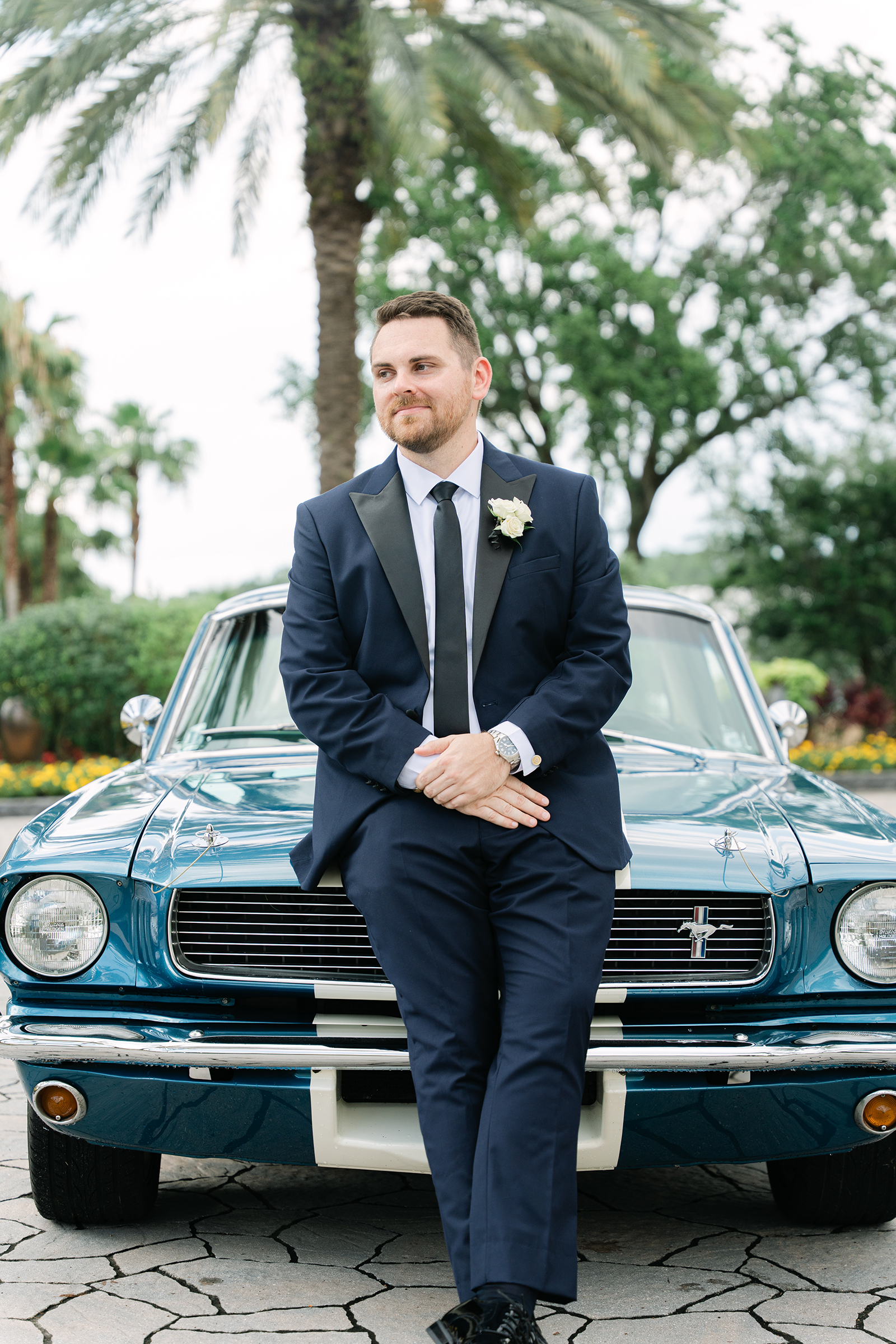 groom wearing navy tux in front of vintage car