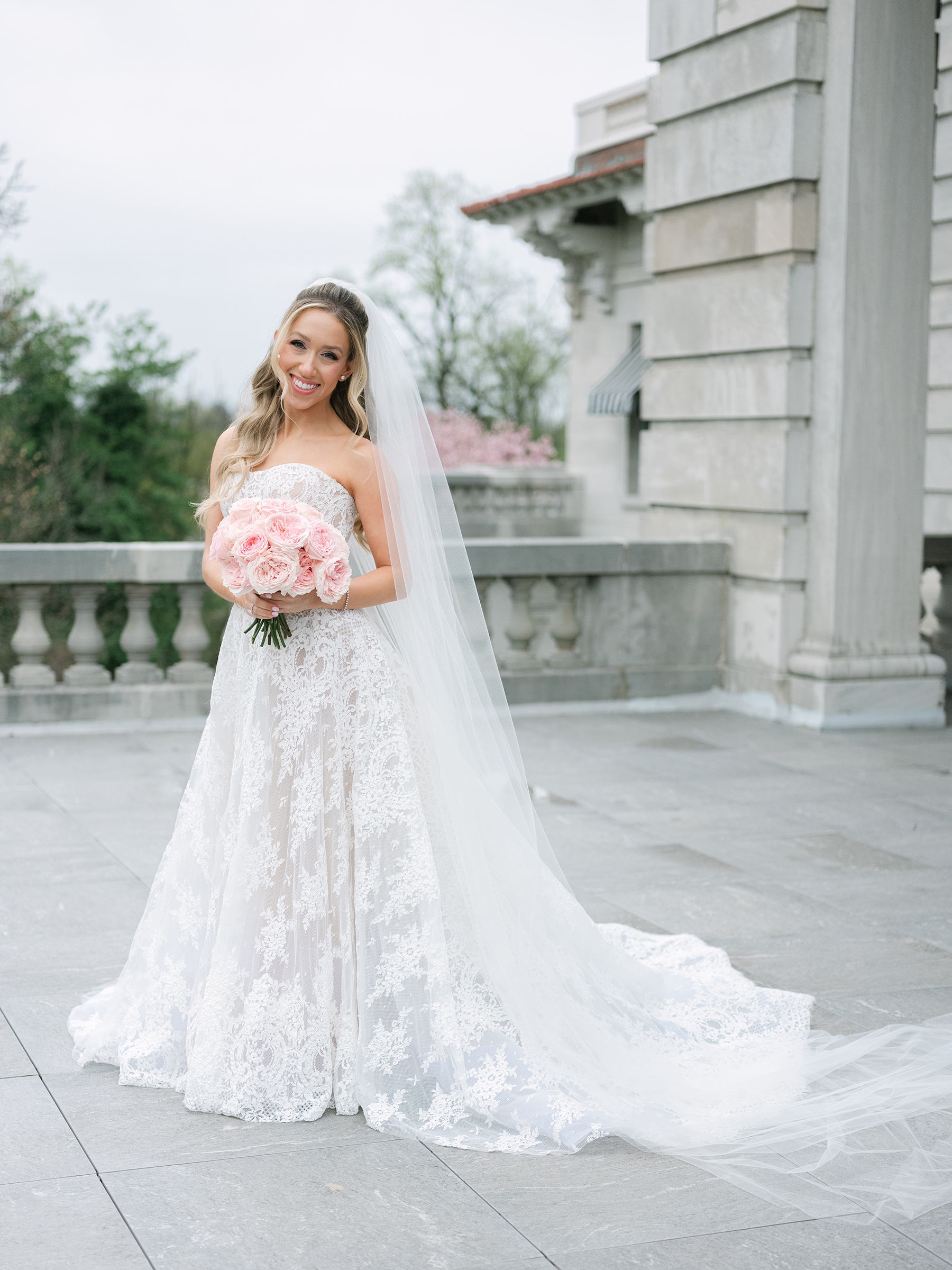 bride wearing white lace wedding dress holding pink bouquet