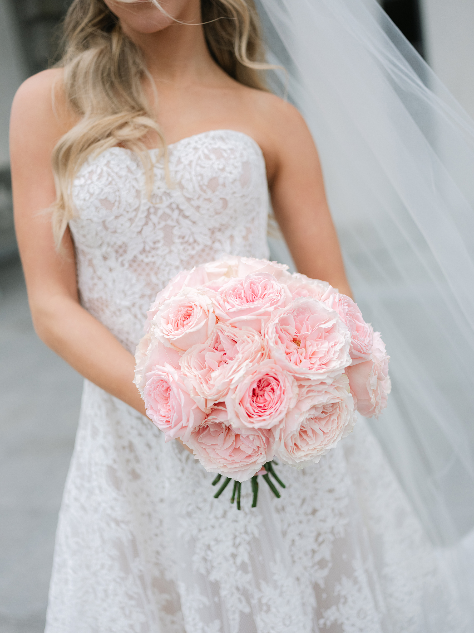 bride wearing white lace wedding dress holding pink bouquet