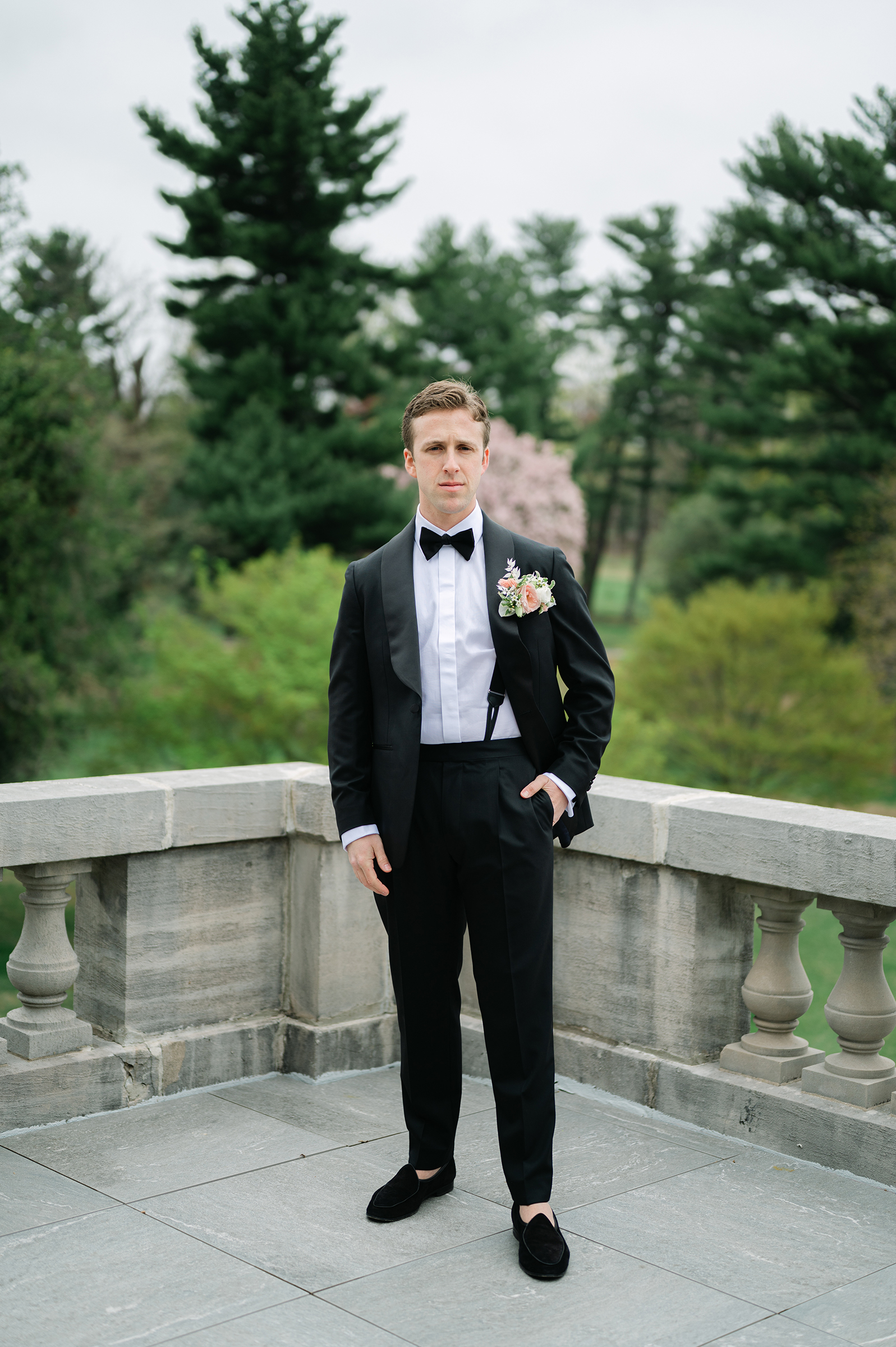 groom in classic black and white suit with pink and white boutonnière