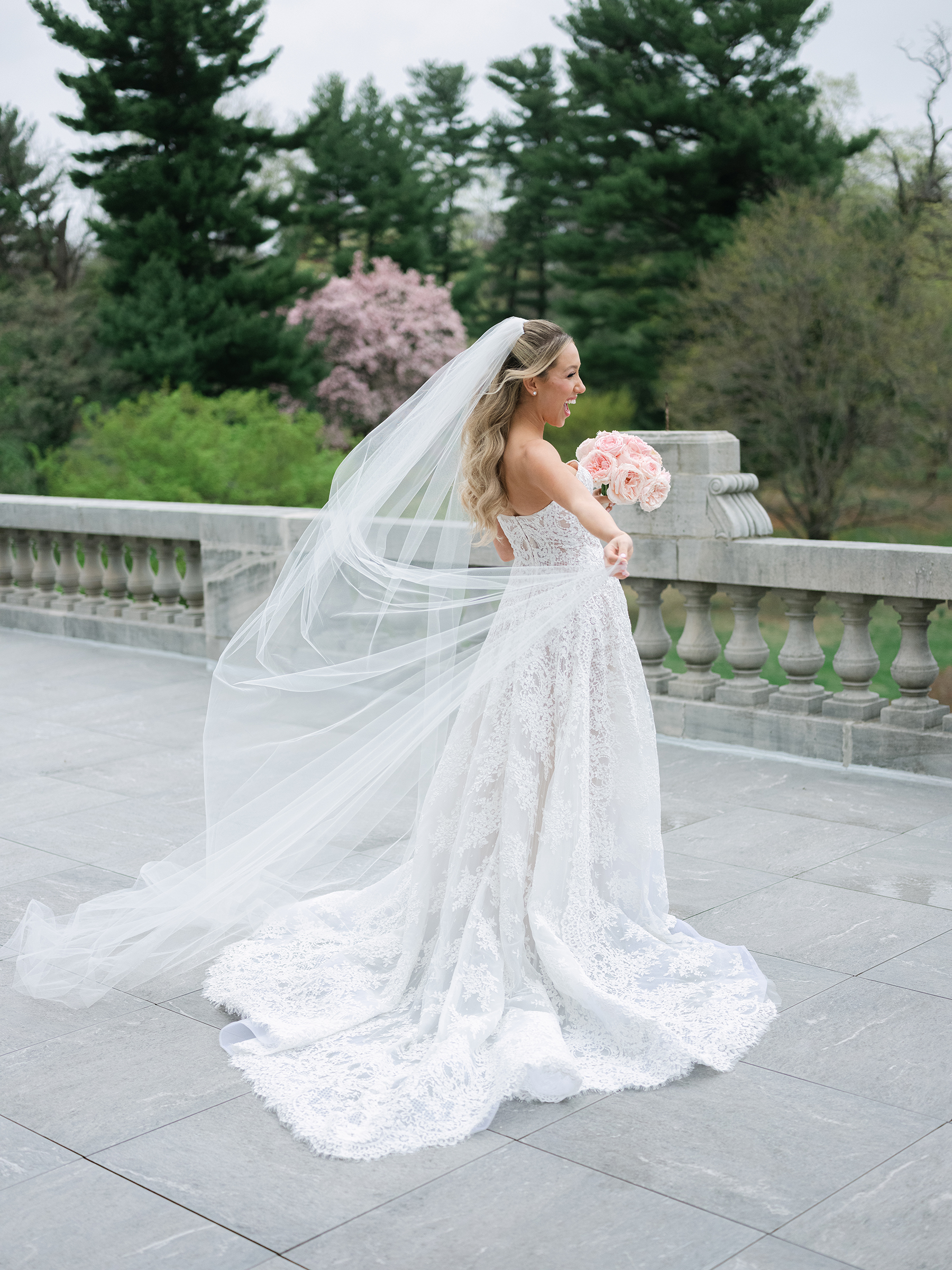 bride wearing white lace wedding dress holding pink bouquet