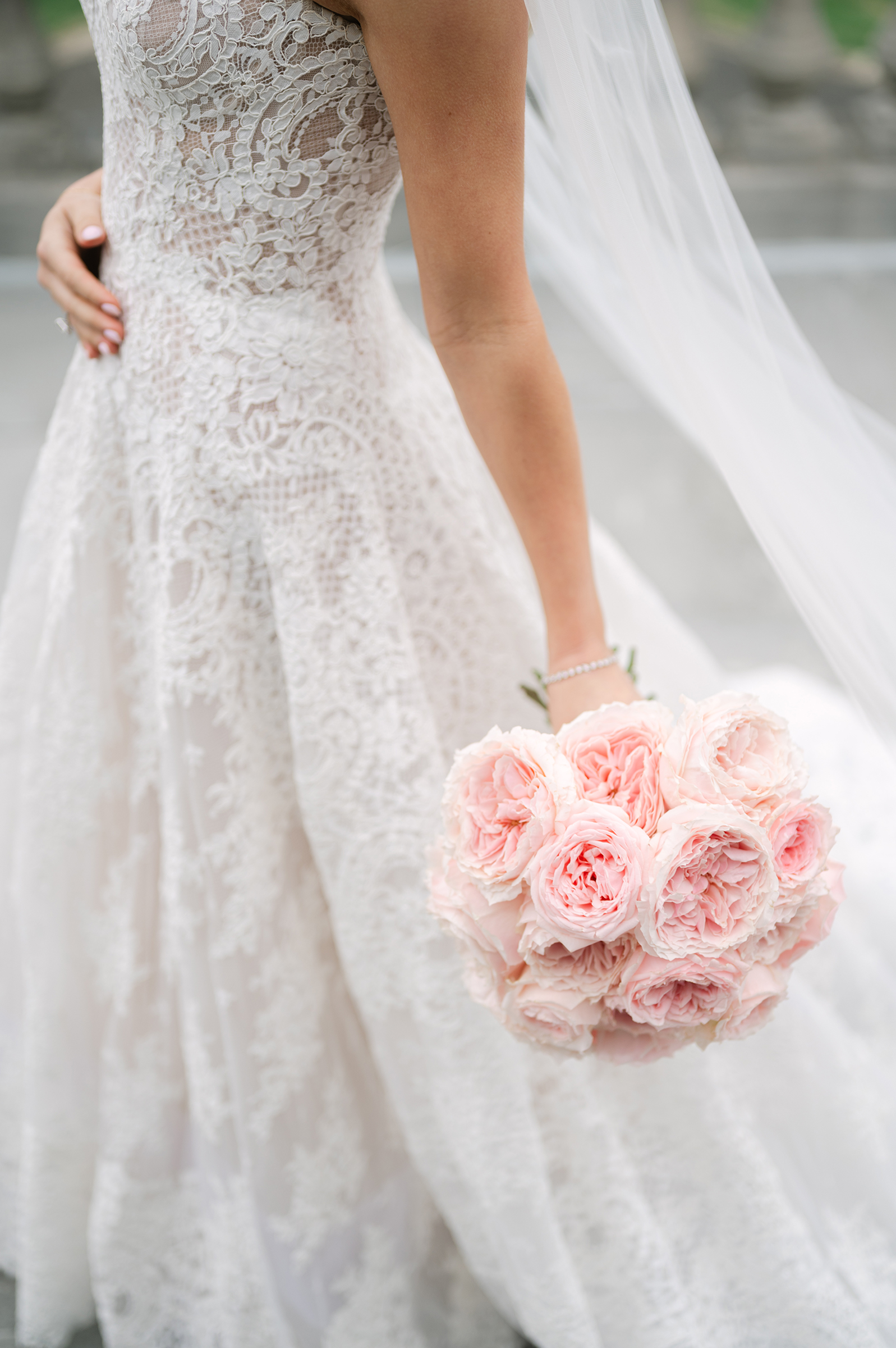 bride wearing white lace wedding dress holding pink bouquet