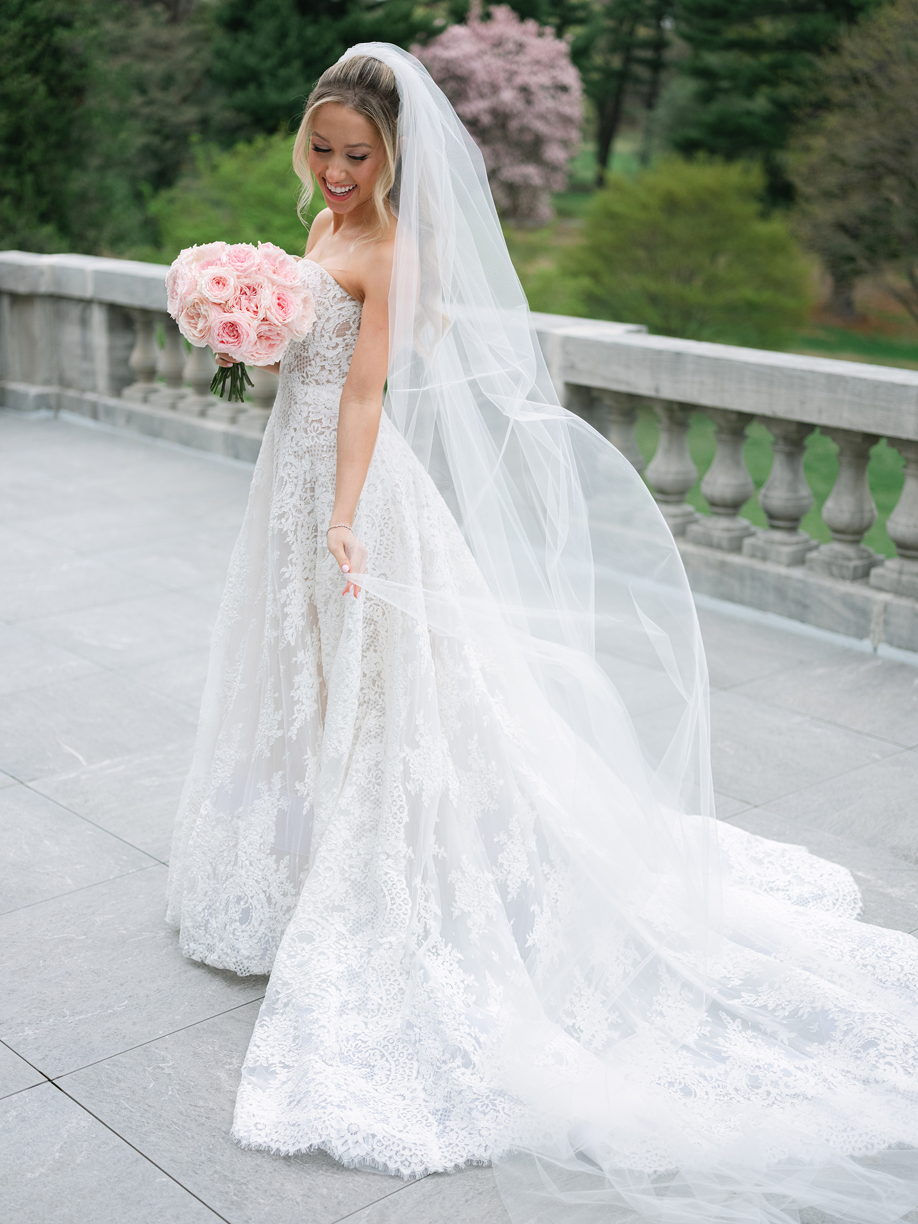 bride wearing white lace wedding dress holding pink bouquet