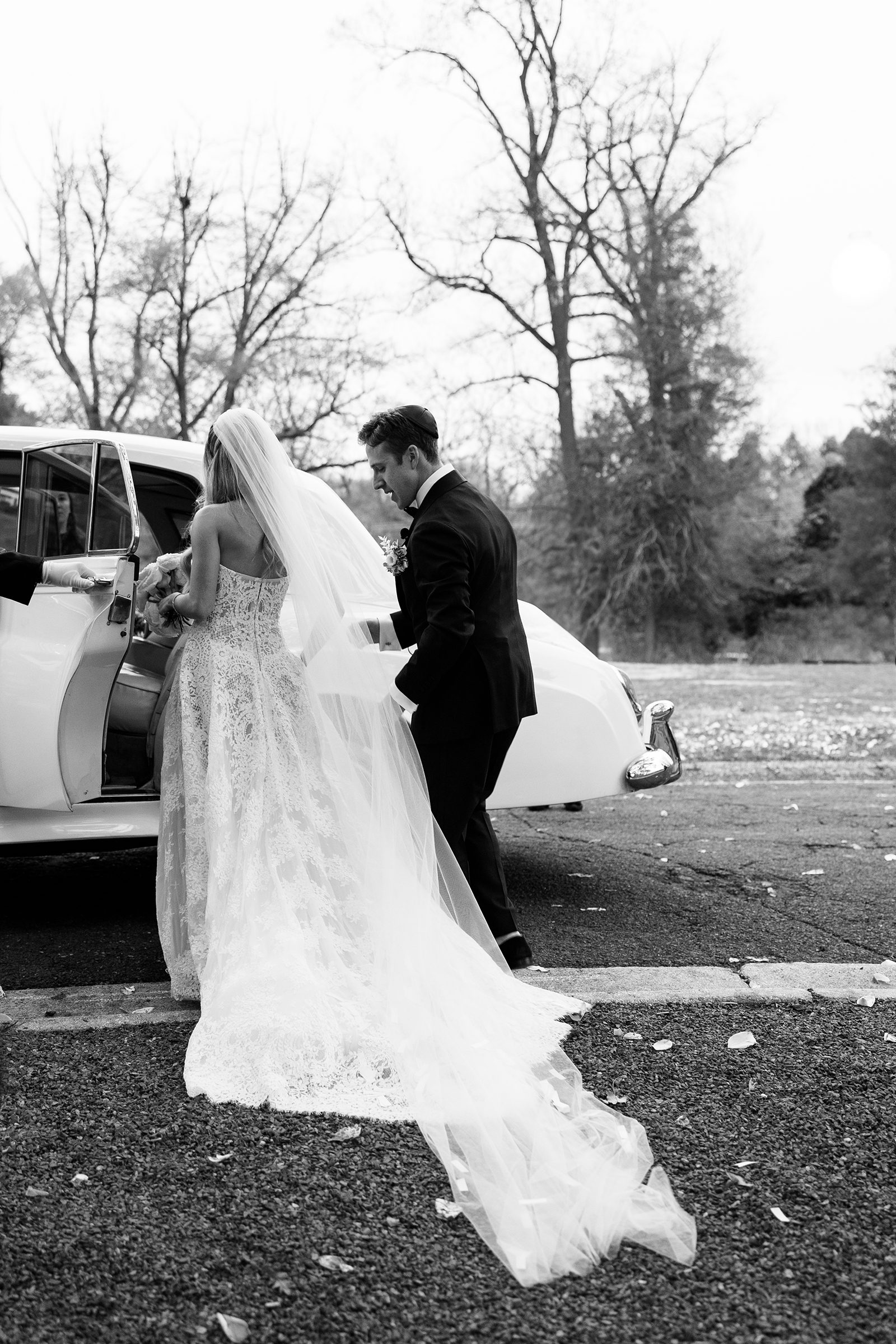 bride and groom entering classic wedding car