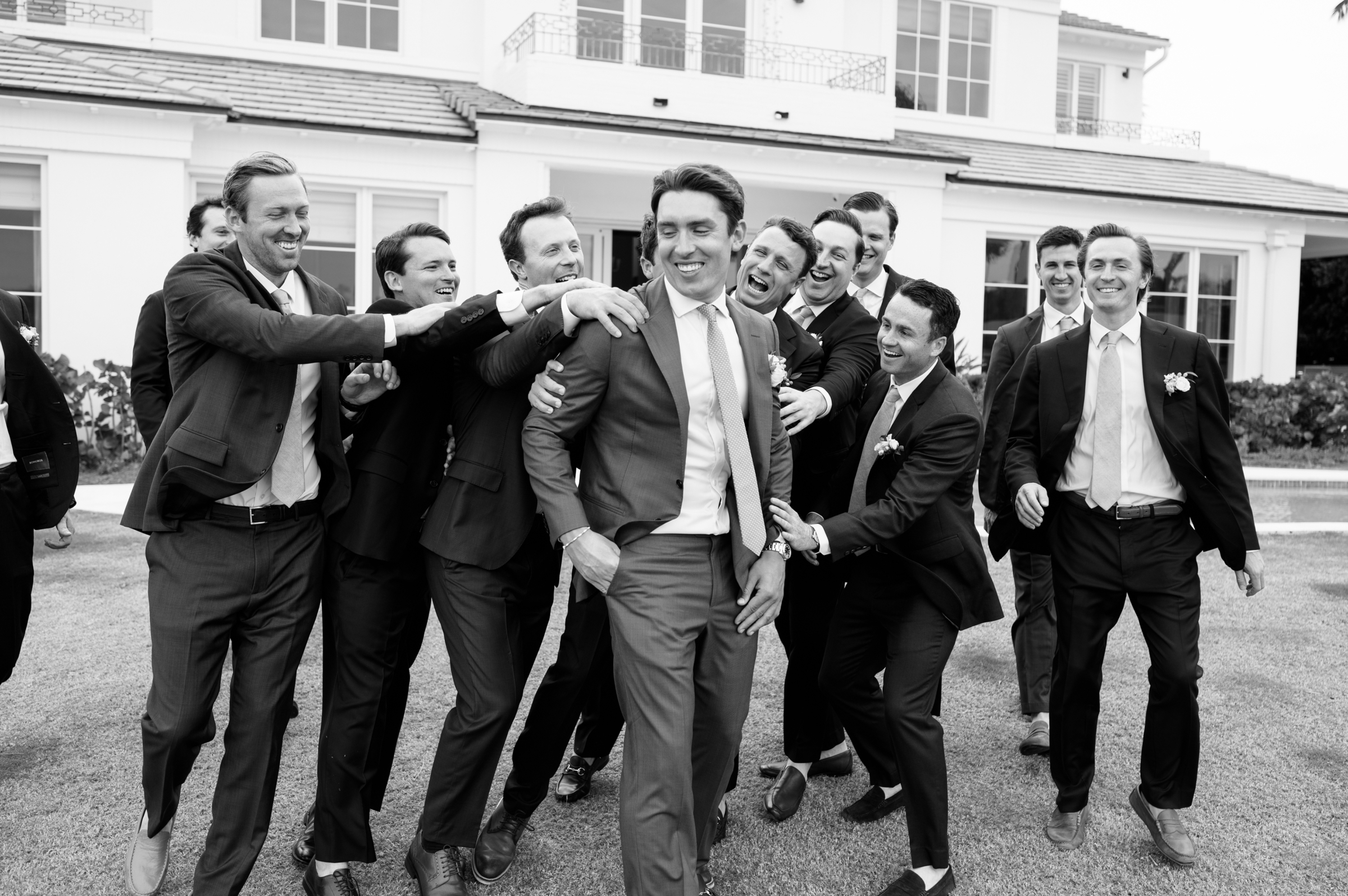 black and white picture of groom walking with groomsmen