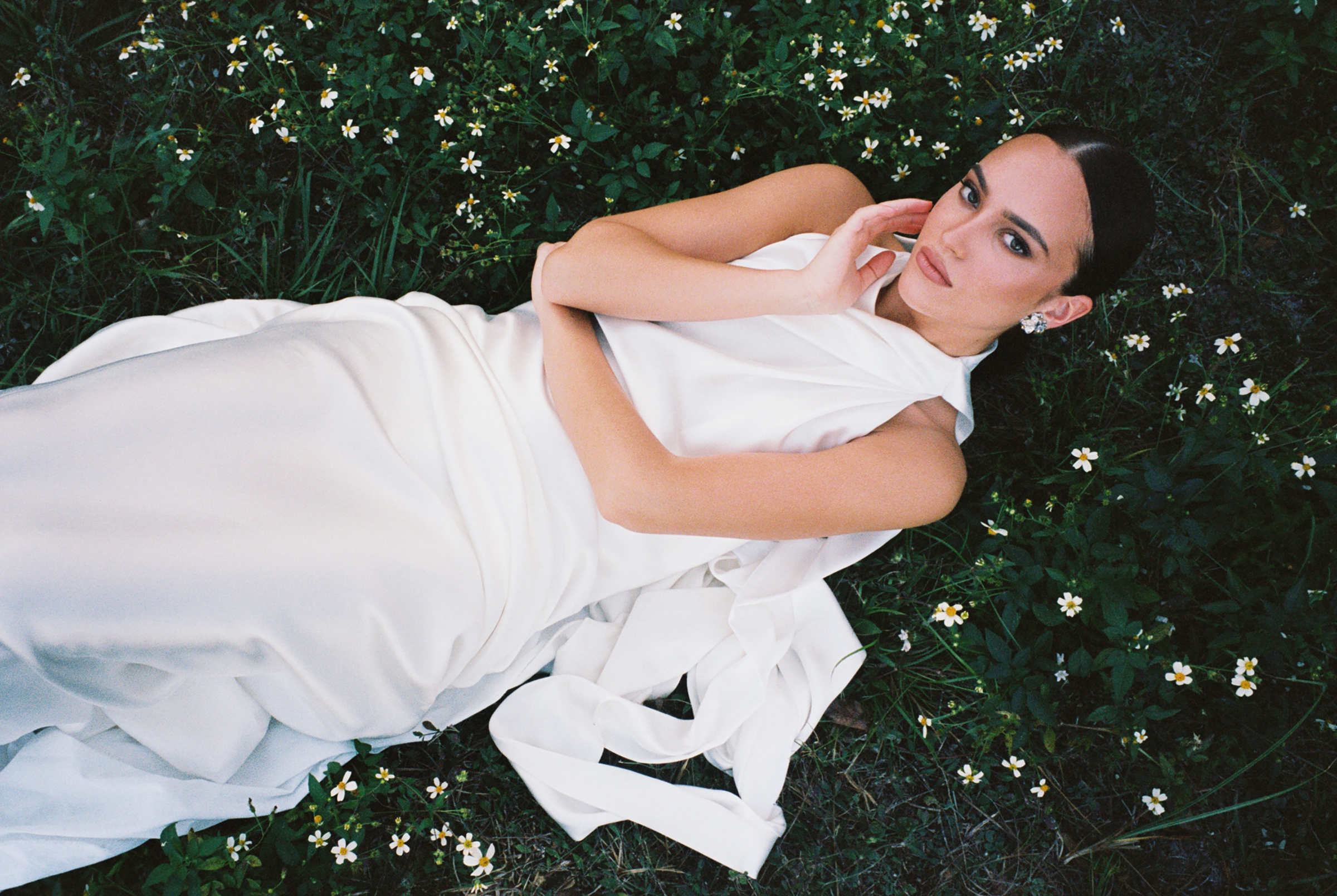 film portrait of woman laying in flower field, wearing wedding dress