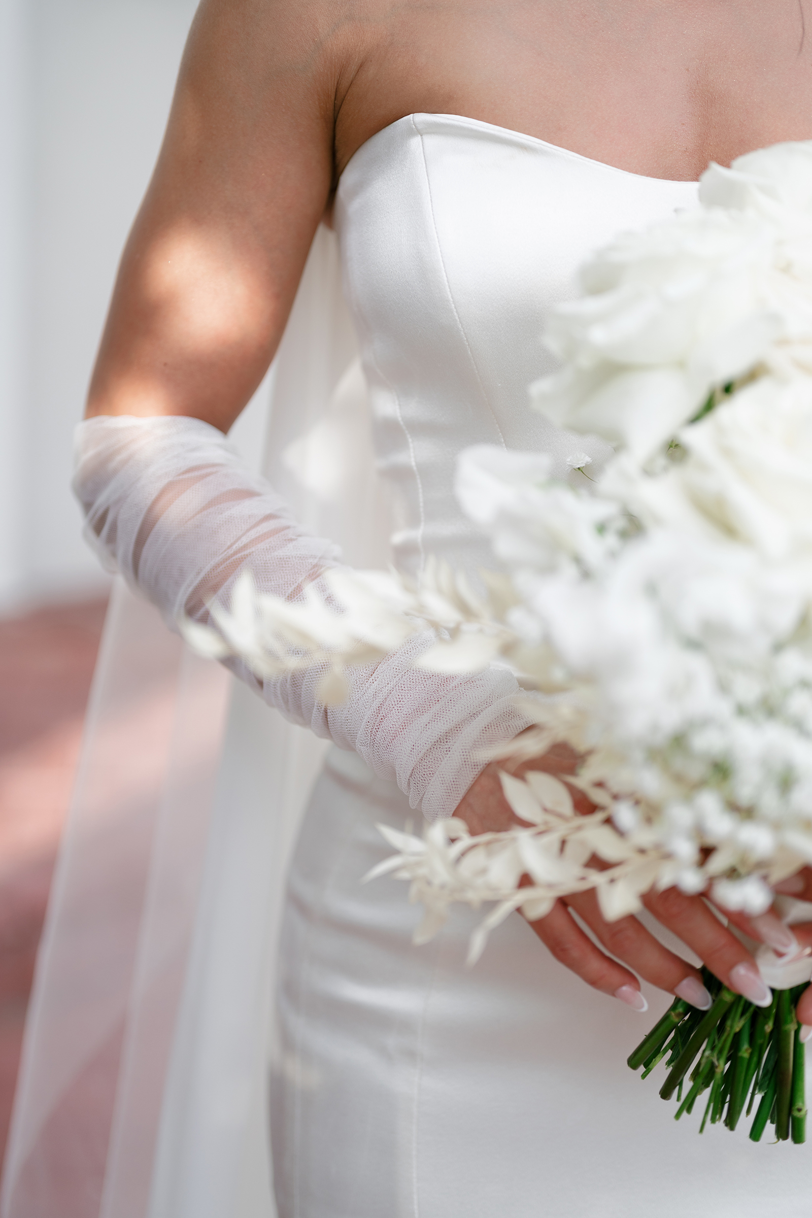 close-up of bride with sheer gloves, white flower bouquet and corset dress top