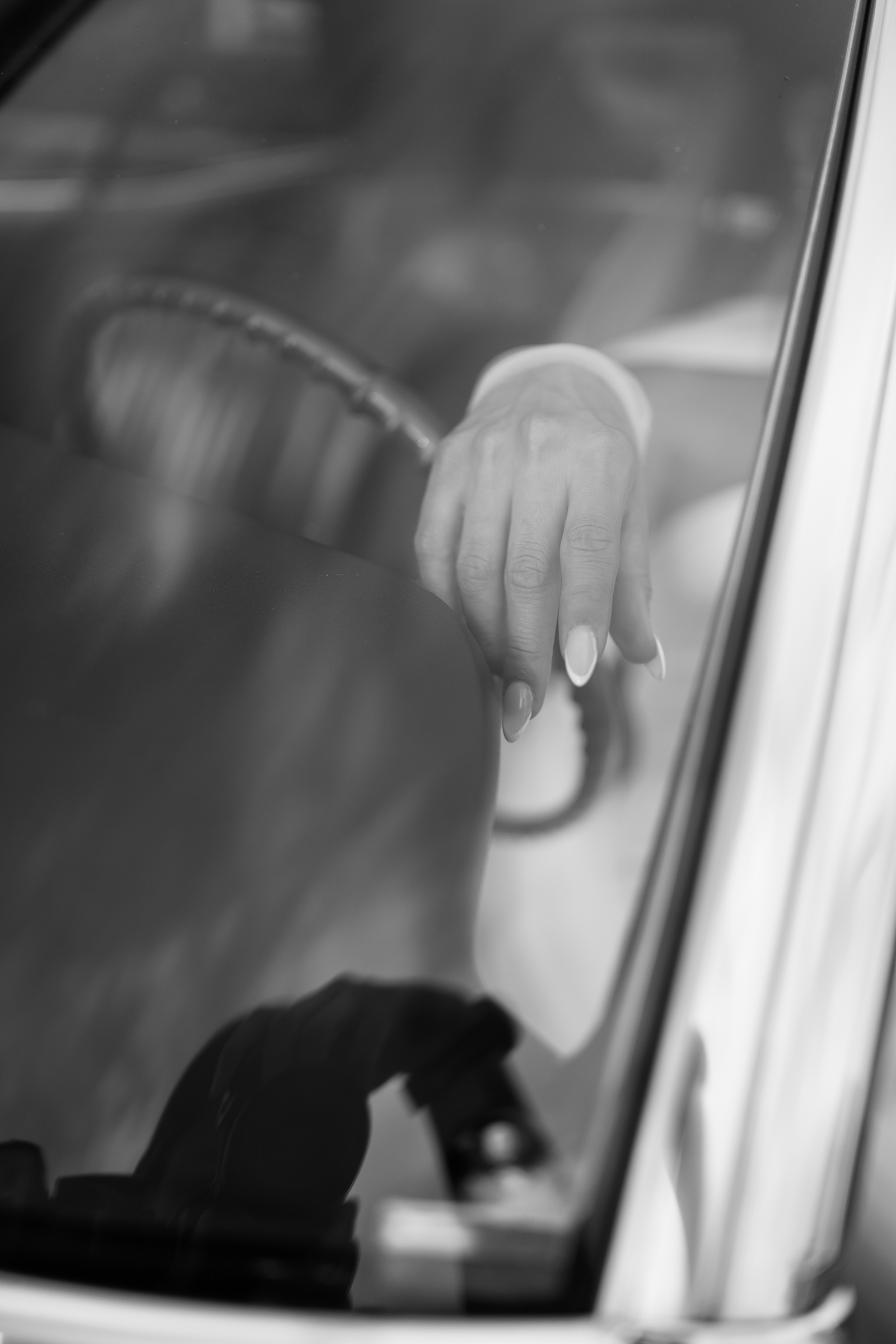 black and white close-up picture of bride with hand on steering wheel