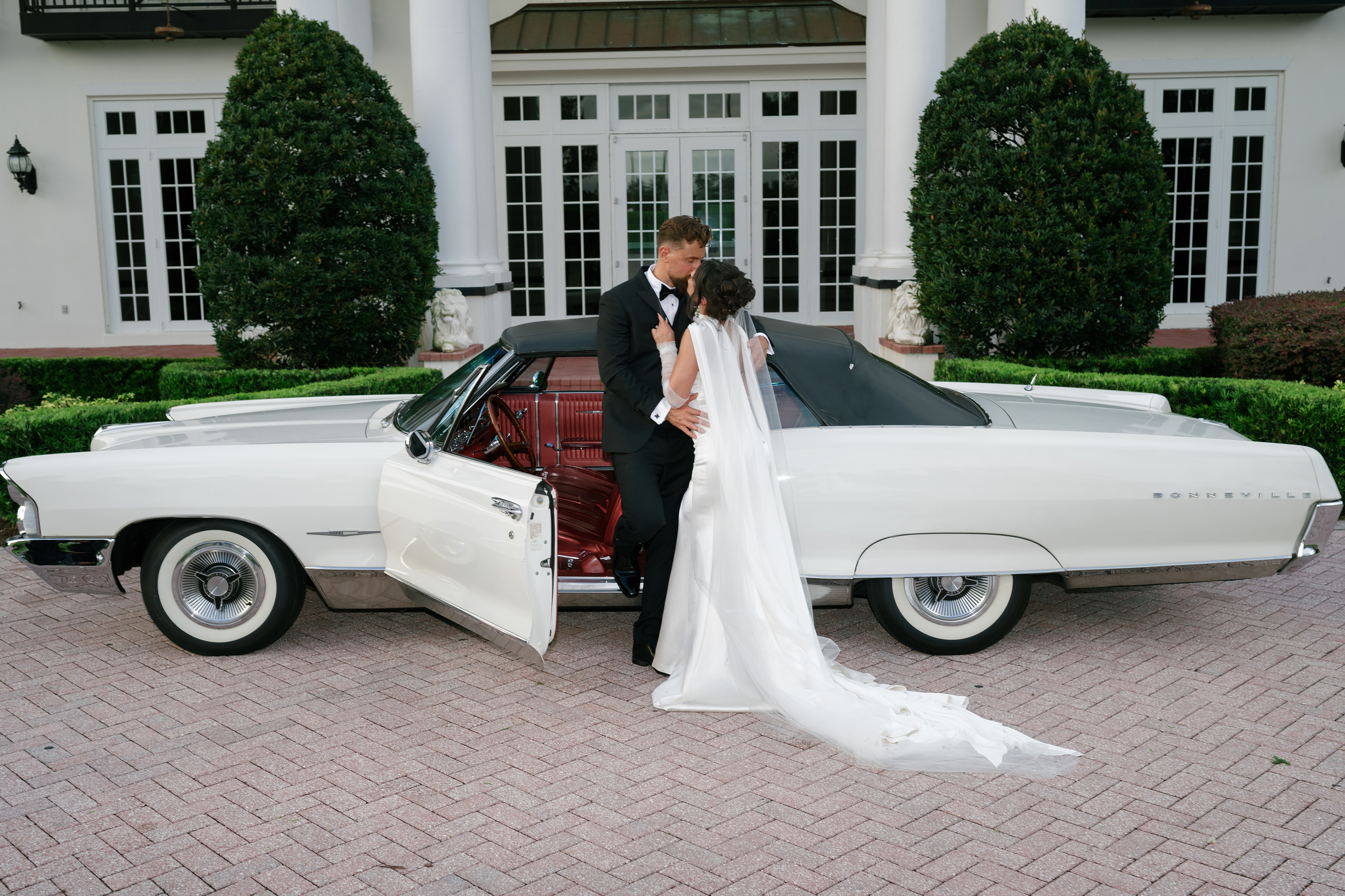 picture of bride and groom in front of luxury car