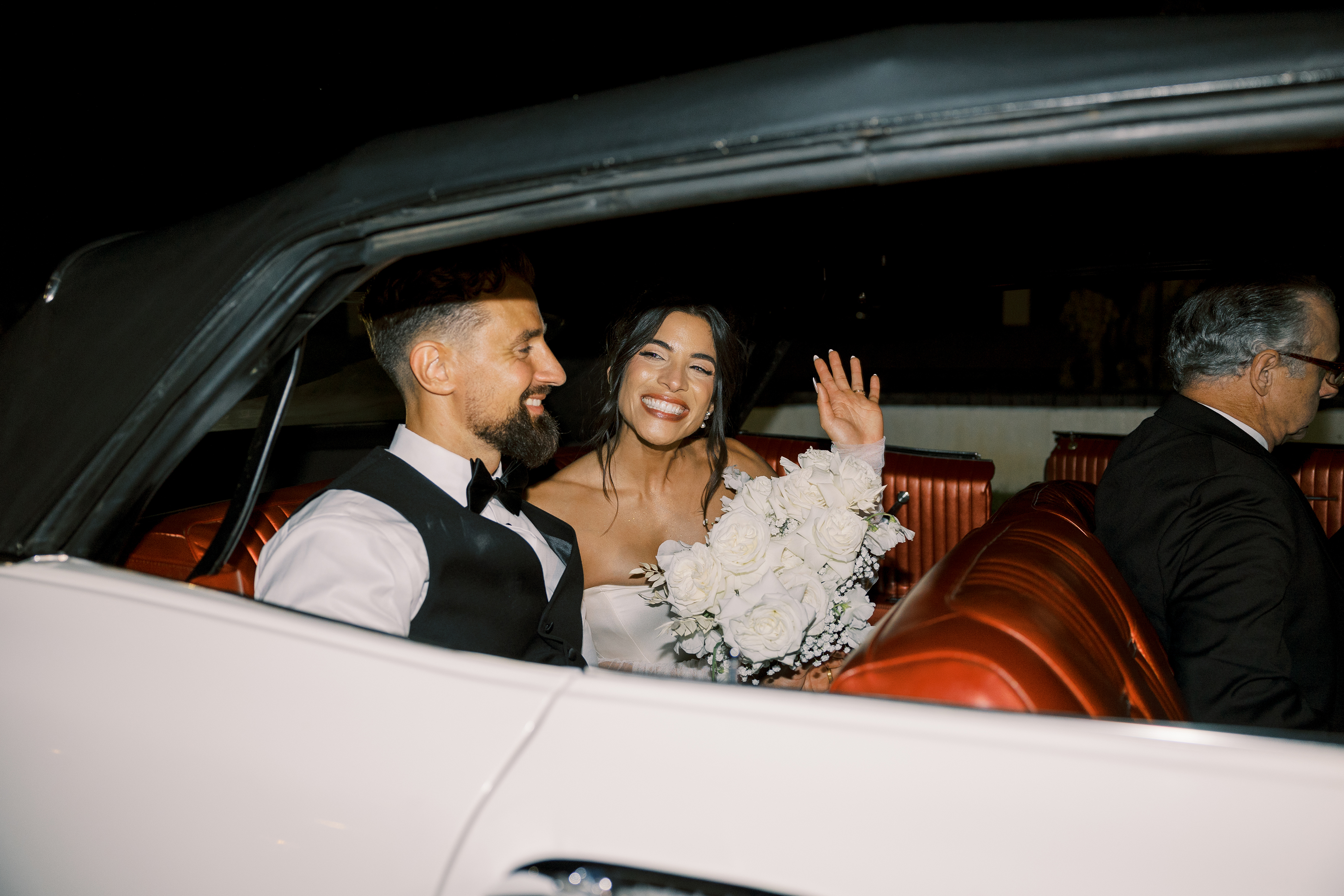 film picture of bride and groom's exit picture in luxury car