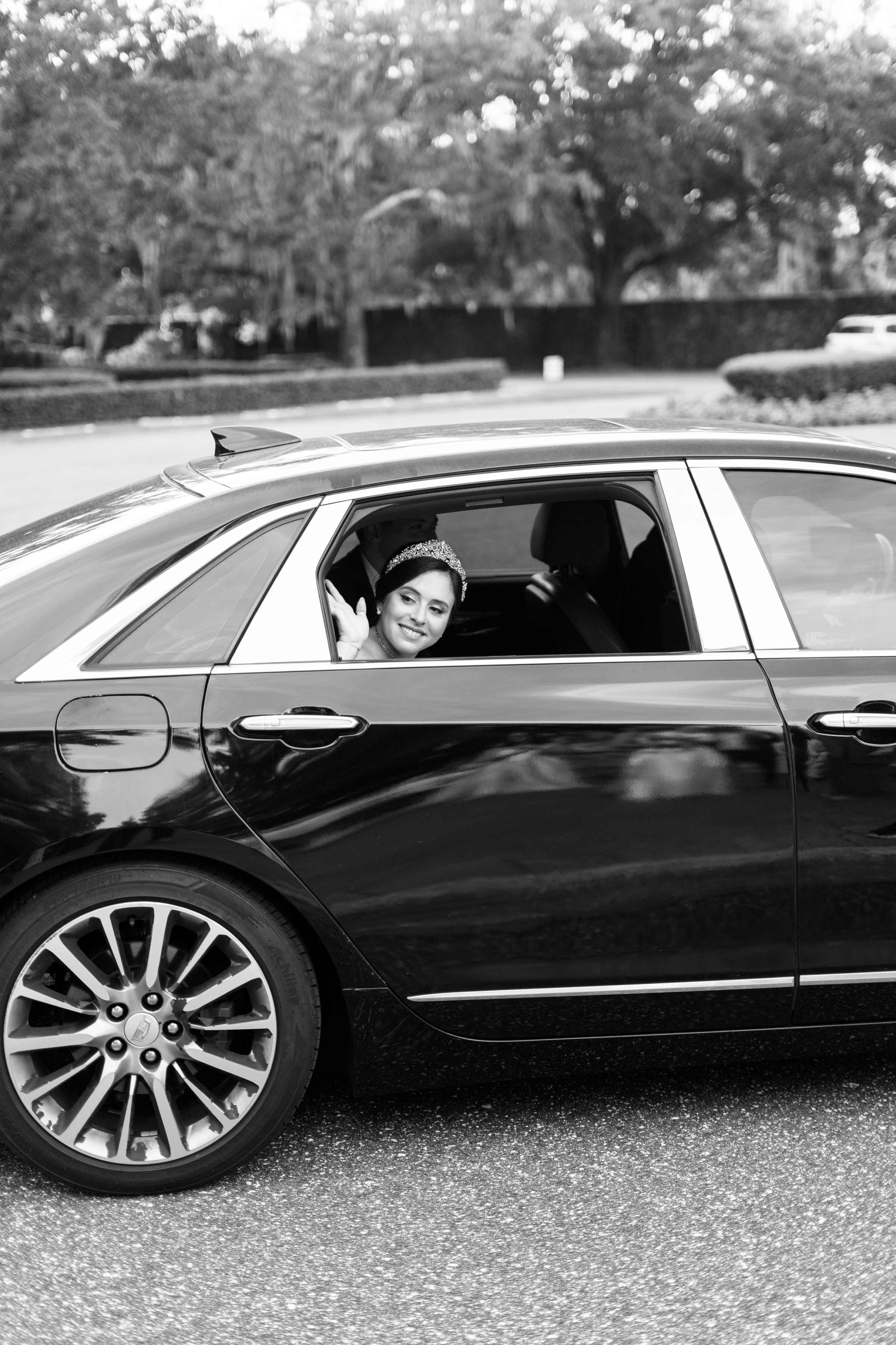 black and white picture of bride exiting with vintage car
