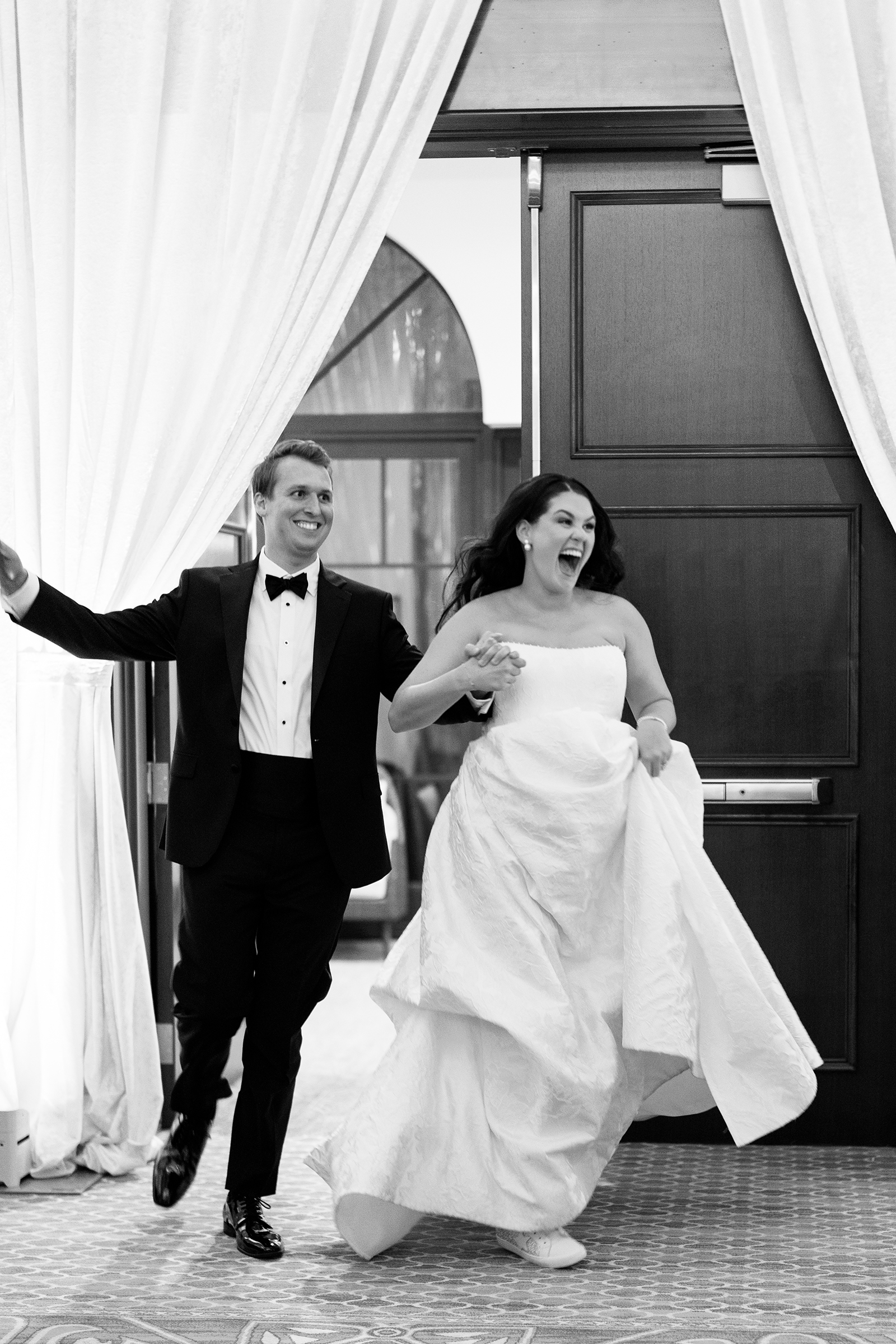 bride and groom running into wedding reception