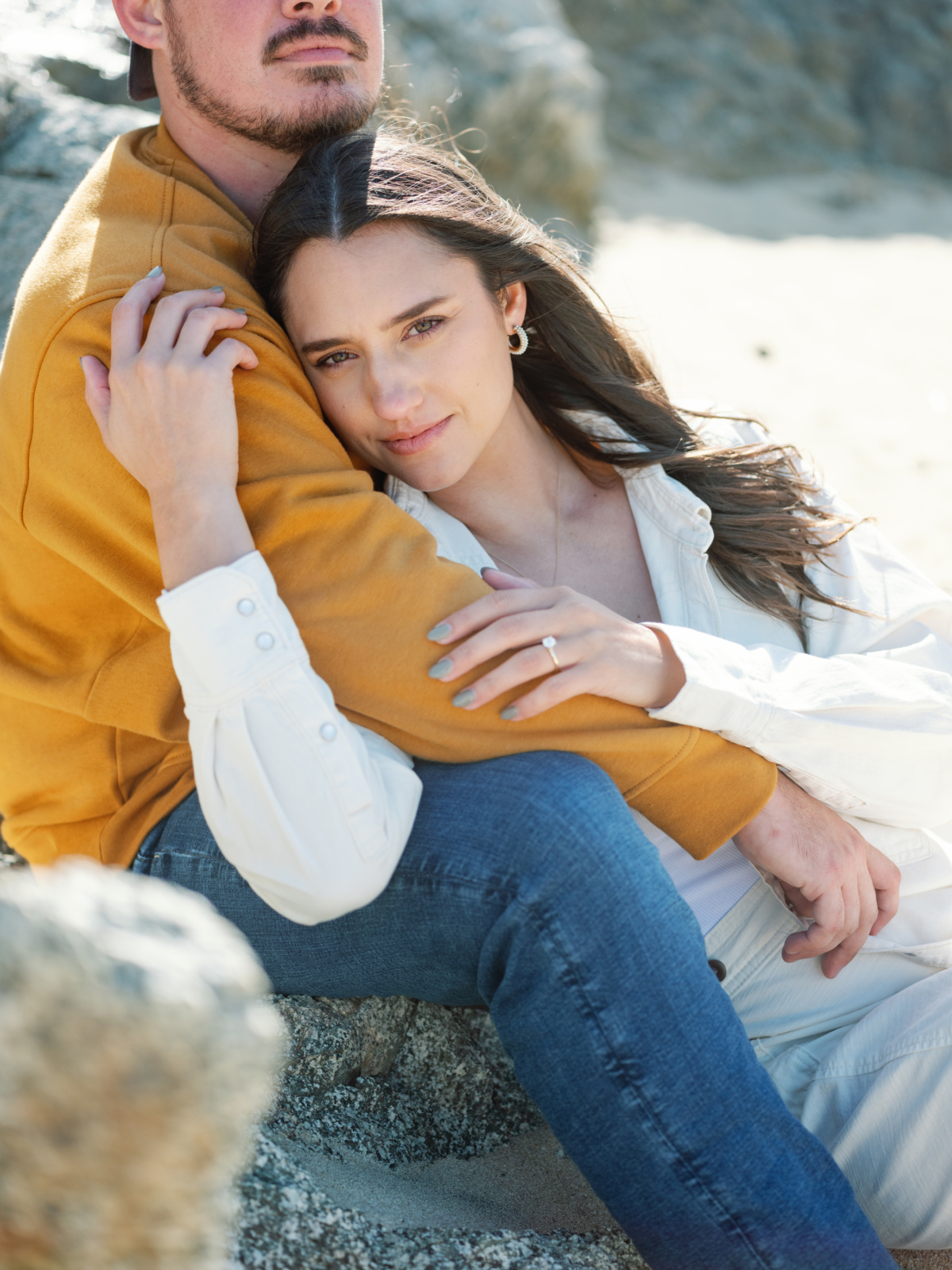 Close-up of a couple cuddling with her engagement ring showing near Carmel, California.