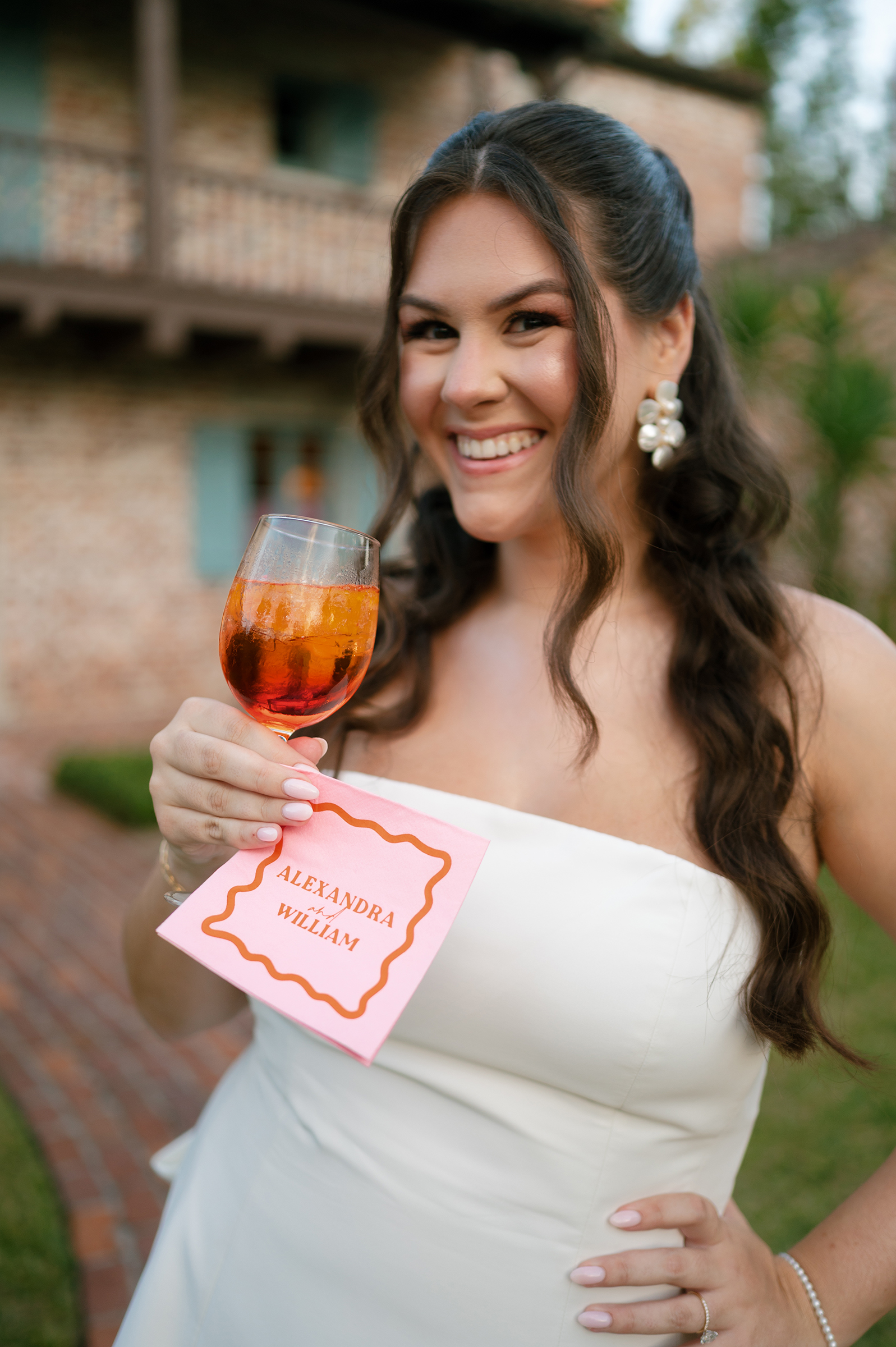 bride holding cocktail and personalized napkin during rehearsal dinner