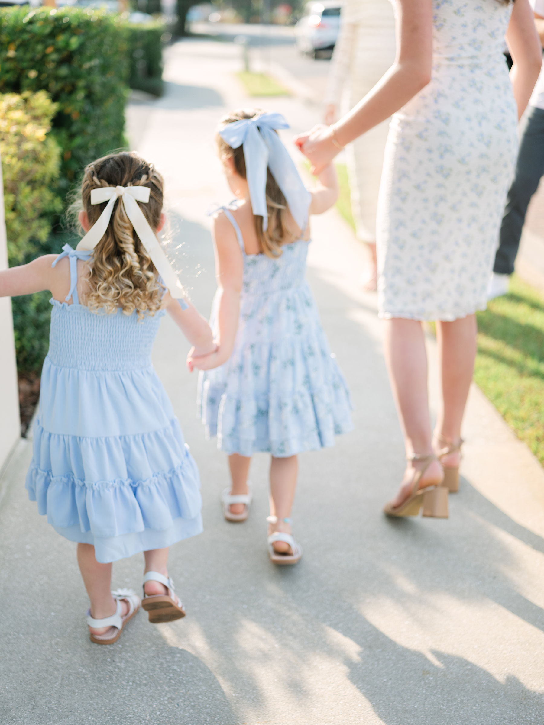 girls wearing muted blue dresses and matching white shoes holding hands