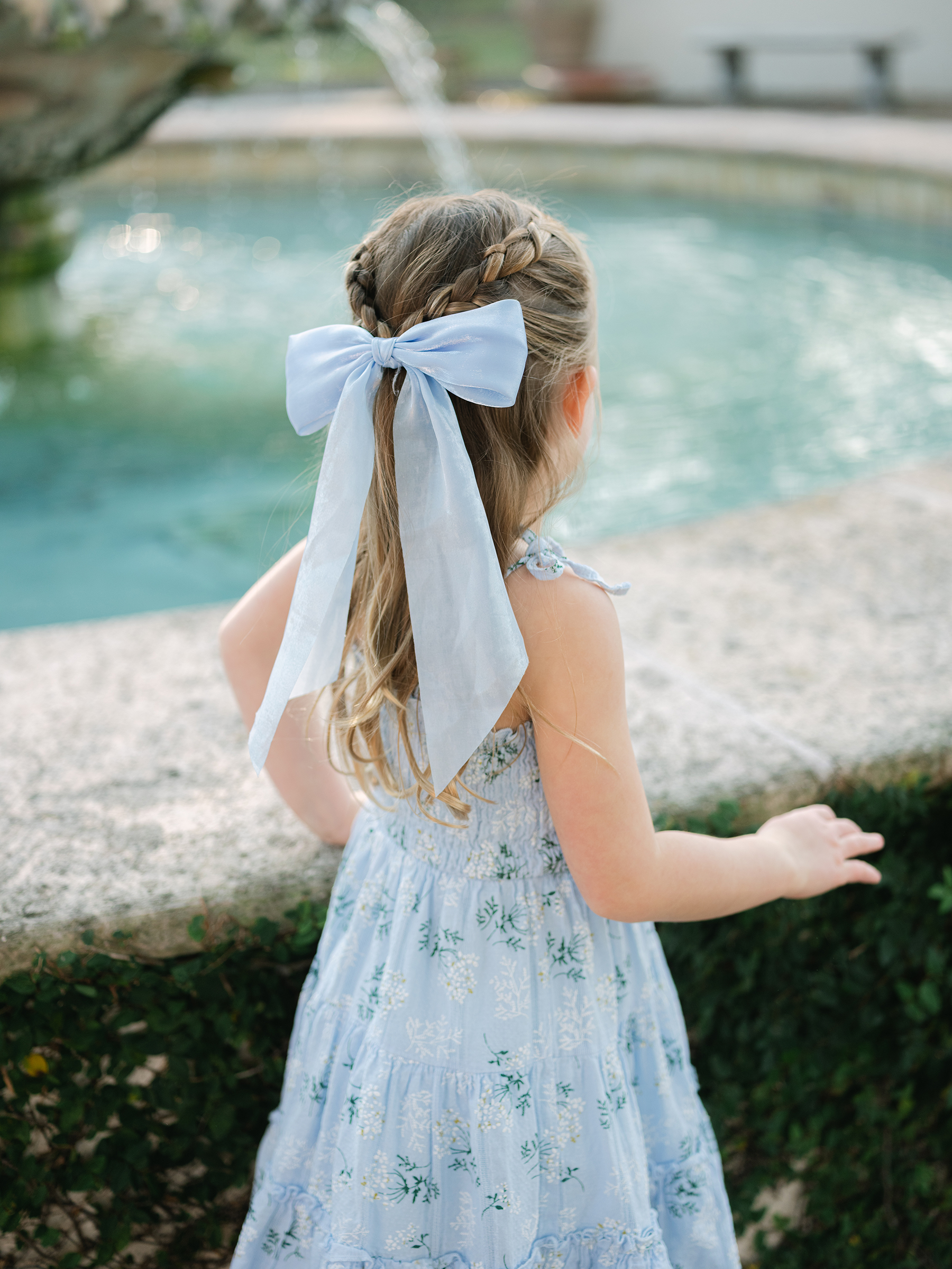 girl in muted blue dress with florals and hair bow