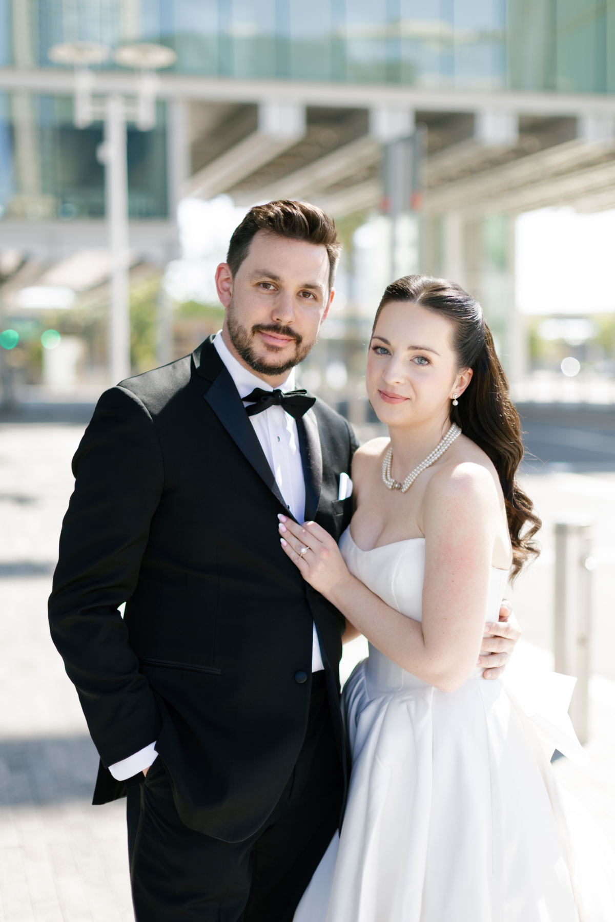 Portrait of the bride and groom in front of the Dr. Phillips Center's glass facade.