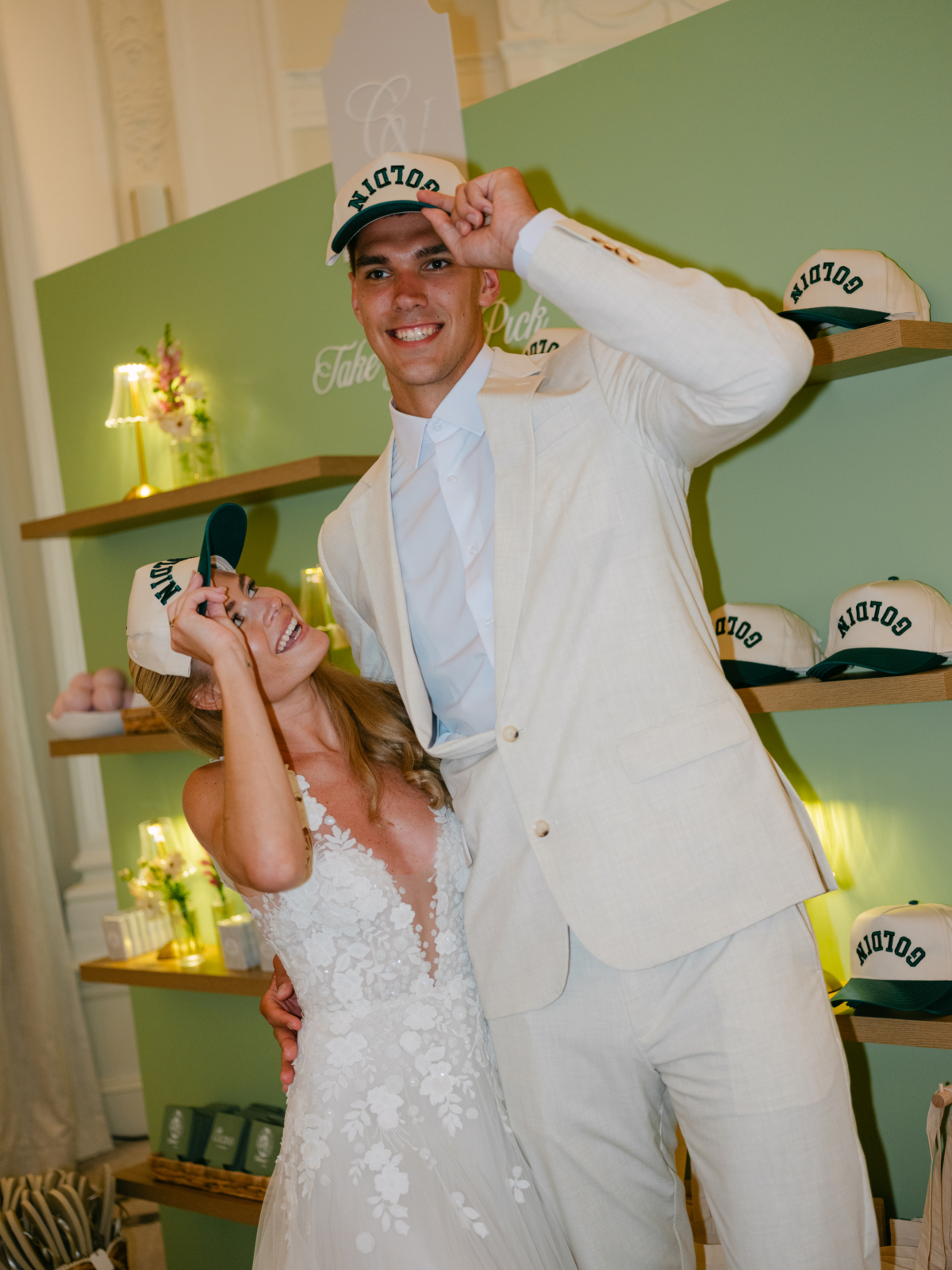 Camryn and Vlad laughing in Goldin hats at the swag wall.