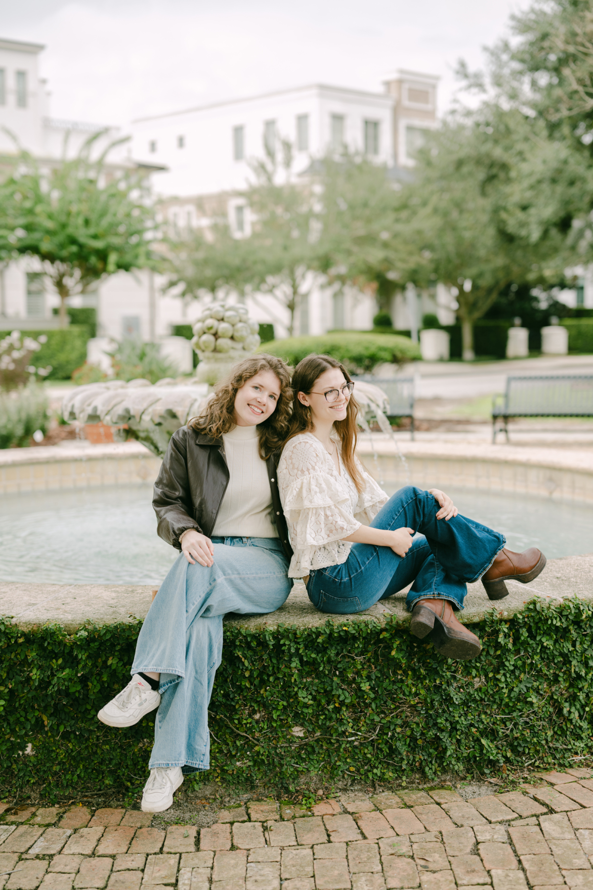 The couple sits together on the ivy-covered ledge of a Winter Park garden fountain under cloudy skies.